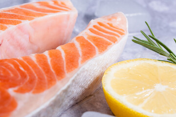 Close-up salmon fillet sits on ice surrounded by lemon slices and rosemary sprigs, the focus is shifted to the fish scales. Healthy nutrition and fish market presentation. side view © HalynaRom