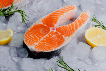 Close-up salmon fillet sits on ice surrounded by lemon slices and rosemary sprigs, the focus is shifted to the fish scales. Healthy nutrition and fish market presentation. side view © HalynaRom