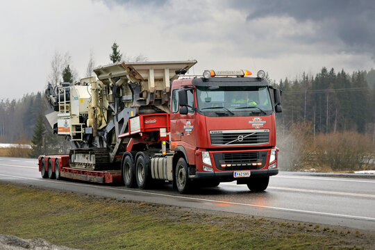Red Volvo FH 520 semi-truck hauls Metso Lokotrack LT1110 Impactor plant on the highway as oversize load.