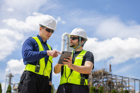 Industrial engineers team discussing work with tablet at refinery plant, Construction manager and worker team checking project data on tablet at industrial site