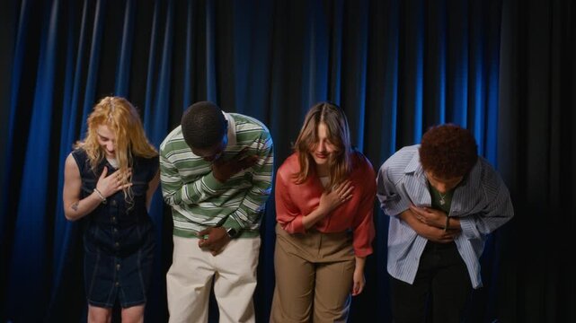 Portrait of diverse young adult student actors placing hands on chest and bowing on theater stage. Footage suitable for drama school advertising, university arts education, or talent show promos