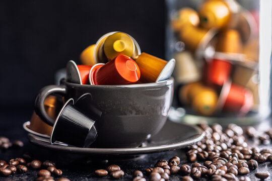 Colorful Coffee Capsules Piled in a Black Cup With Scattered Coffee Beans for Espresso Lovers