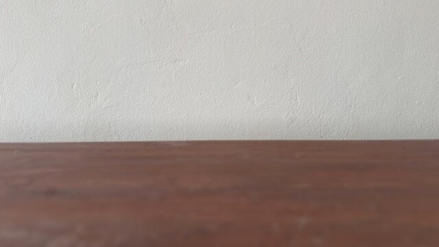 Empty brown wooden table surface against a clean light wall