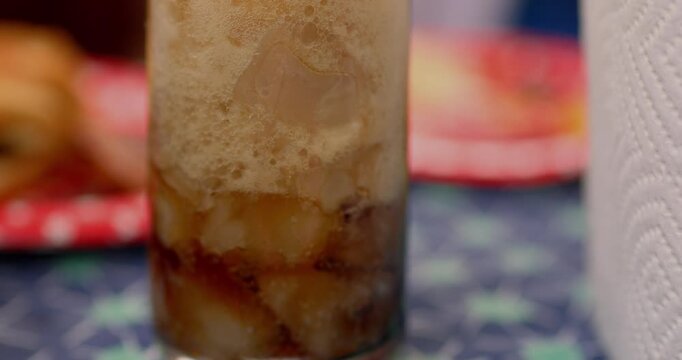 Watching an ice cold glass of cola soda pop beverage fizz on the picnic table waiting to be filled with more beverage filmed in cinema 4K 30fps slowed from 120fps