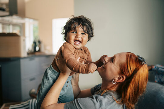 Happy mother playing with her toddler baby during house relocation