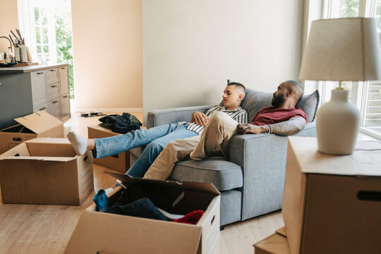 Father and son taking break while sitting on sofa during house relocation