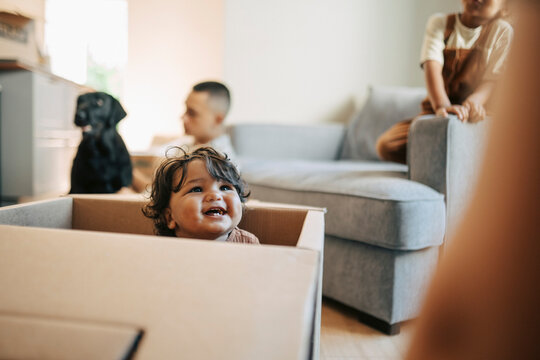 Cute toddler sitting inside cardboard box during house relocation