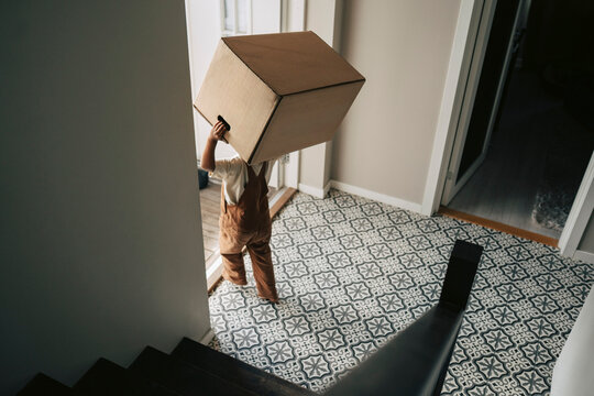 High angle view of boy carrying large cardboard box during house relocation