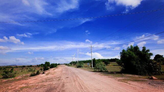 A journey through Hoa Thang, Lam Dong shows a view of open roads and blue skies. The landscape is vast with trees on both sides. Enjoy the beauty of the countryside at midday.