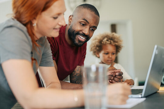 Diverse parents using laptop to plan their house move