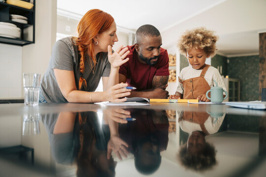 Diverse parents looking at son playing with level tool in new home