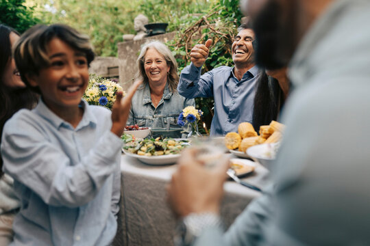 Multi-generational family laughing together during backyard lunch party