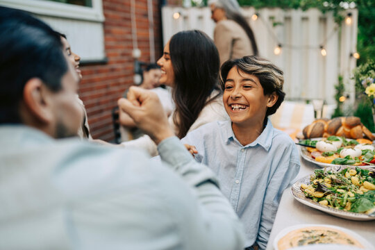 Smiling boy celebrating and playing with his father at dining table