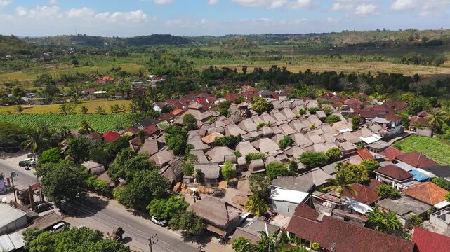 Sade Traditional Village in Lombok, Indonesia, before the August 2026 fire, showing historic Sasak thatched-roof houses surrounded by tropical farmland, aerial reveal