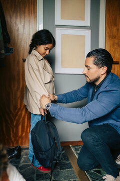 Father adjusting jacket of her daughter before leaving home