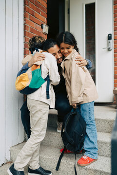 Father embracing his two children at doorstep before leaving for school