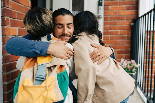 Loving father embracing his son and daughter outside their house