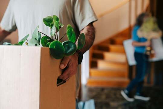 Midsection of man holding cardboard box while while moving in new apartment