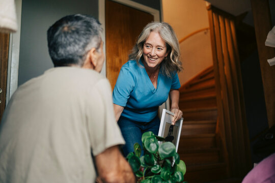 Smiling woman helping man picking belongings while moving into new home