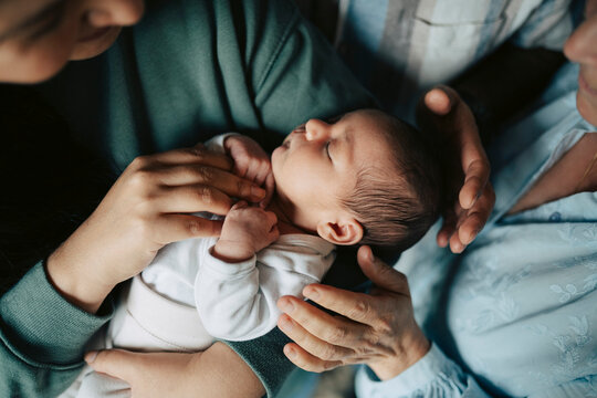 High angle view of cute newborn infant sleeping in her mother's arms