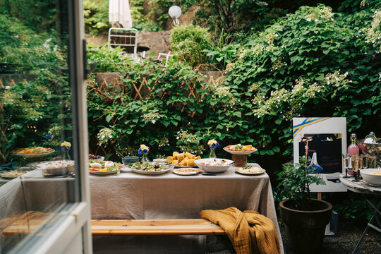 Long dinner table filled with food for celebration in green backyard