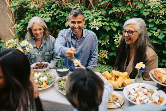 High angle view of happy grandfather playing with grandson at family dinner party