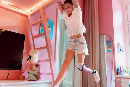 Full length of girl with prosthetic leg playing in her bedroom