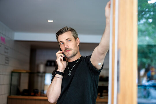 Bakery owner talking on smart phone while standing near doorway