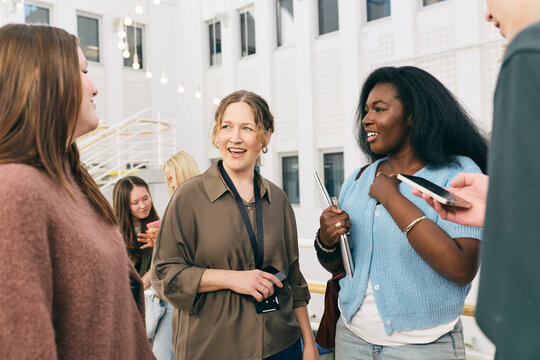 Female college teacher talking with her students in lobby