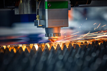 Obraz premium Industrial CNC laser cutting machine with flying sparks in metal fabrication.