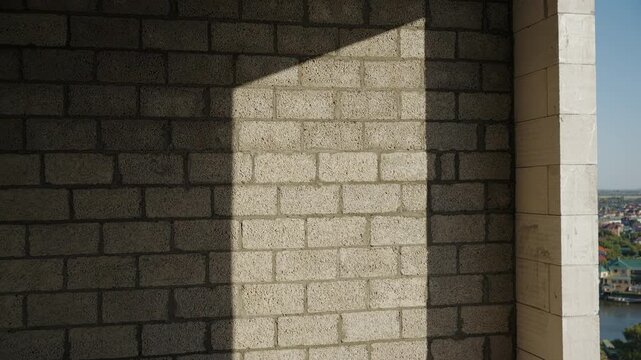 Zoom out from geometric sunlight on unfinished masonry wall