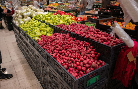 Fresh red radishes and green peppers on market vegetable counter.