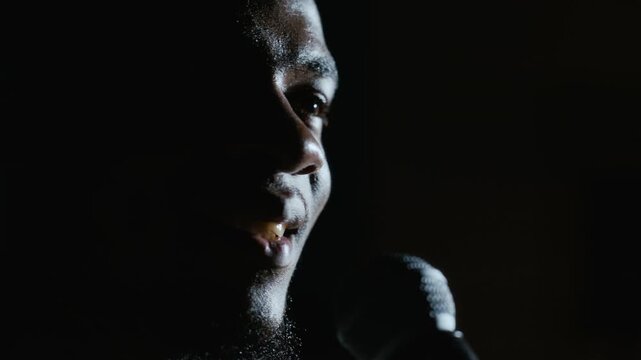 African American young man speaking into microphone during theater performance in extreme close up. Clip suits acting marketing, performing arts campaigns, and drama promotions