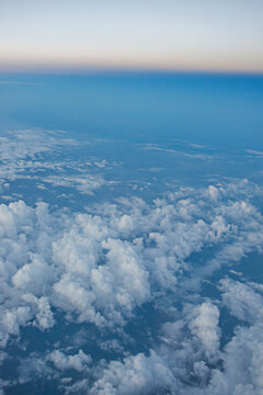 Aerial view of a rolling cloud carpet stretching toward a hazy dusk horizon, with no aircraft in frame.