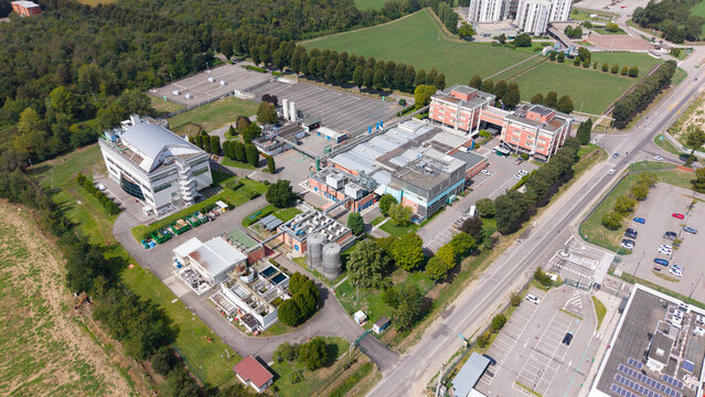 Aerial view of the STMicroelectronics industrial facility featuring modern buildings, parking areas, and surrounding green spaces in Cornaredo, Lombardia, Italy.