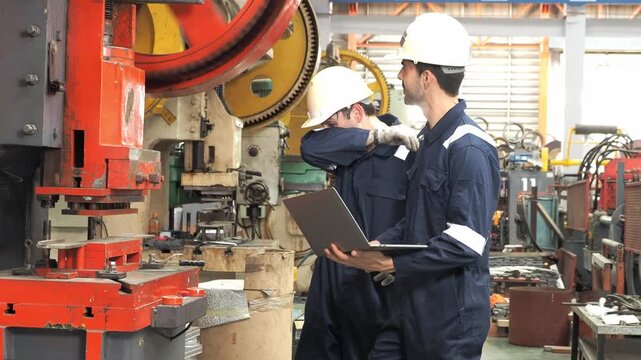 professional mechanical engineer technician protective overall hardhat collaborate inspect heavy industrial machinery  check diagnostic data laptop computer during maintenance operations inside metal 