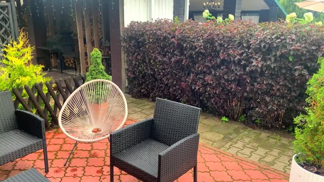 Modern backyard patio featuring stylish pink Acapulco chairs, outdoor umbrella, lush green garden landscaping, and cozy seating area for summer relaxation.