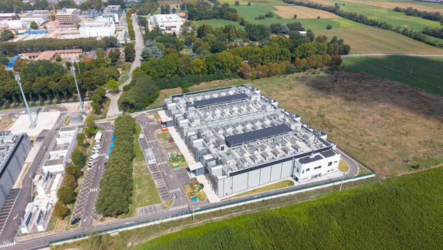 Aerial view of the DATA4 MILAN CAMPUS, a modern data center with rooftop cooling units and solar panels, surrounded by parking and fields in Zona Industriale, Lombardia, Italy.