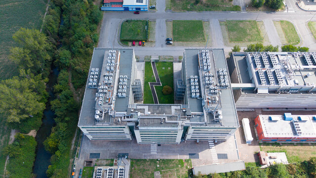 Aerial view of a data center complex with rooftop HVAC units, a central courtyard, and surrounding greenery in Settimo Milanese, Lombardy, Italy.