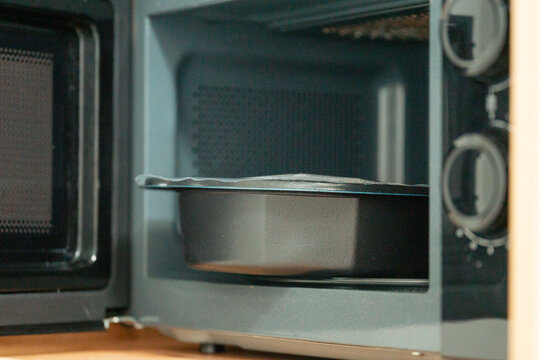 baking dish with lasagna or pie inside an open microwave oven or mini oven kitchen appliance concept of food preparation cooking