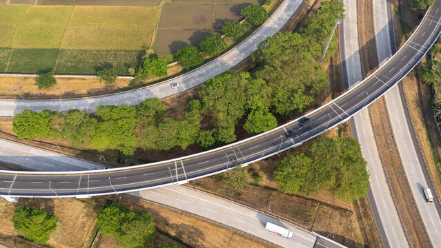 Aerial view of a curved highway interchange surrounded by lush green trees and agricultural fields in Boyolali, Central Java, Indonesia.