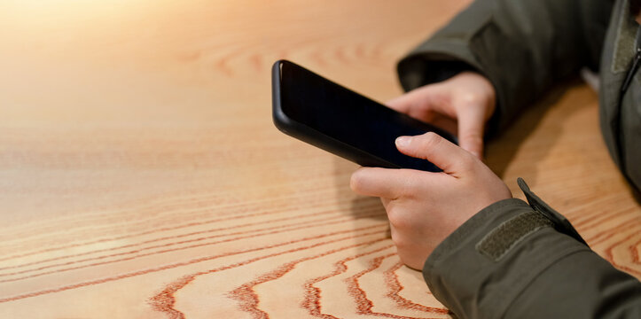 Child hands using smartphone at wooden table in winter clothing, mobile technology and digital communication with copy space for autumn, back to school, education and online lifestyle.