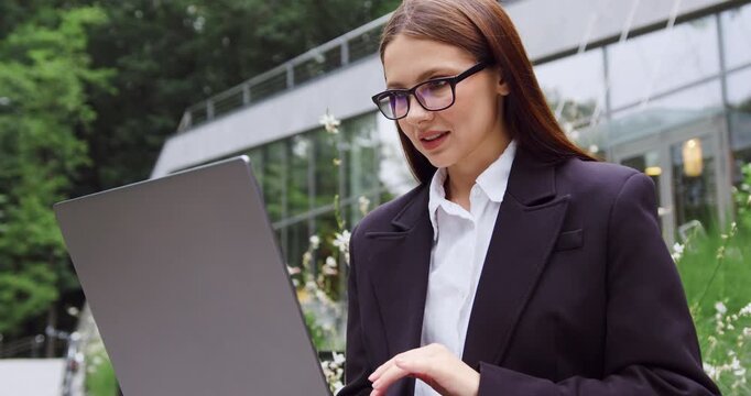Young business woman working on laptop in urban park
