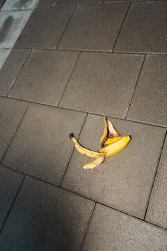 High angle view of discarded yellow banana peel lying on paved city sidewalk