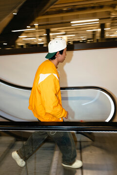 Side view teenage boy moving down from escalator