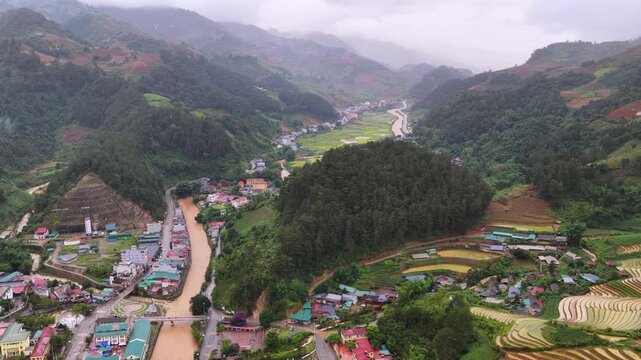 Aerial drone view of a river winding through the mountainous landscape and rice paddies of Mu Cang Chai, Vietnam.