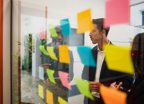 Multiracial colleagues working inside business office with glass walls - Entrepreneurs people sharing ideas at teamwork meeting - Brainstorming concept - Main focus on center man face - UGC content