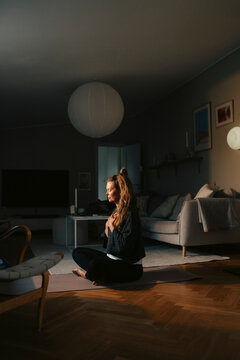 Full length of woman doing Yoga while sitting in living room at home