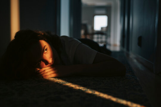 Depressed young man contemplating while lying on floor at home