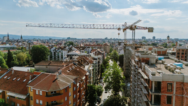 Aerial view of a construction crane towering over residential buildings and rooftops in the city of Novi Sad, Vojvodina, Serbia.